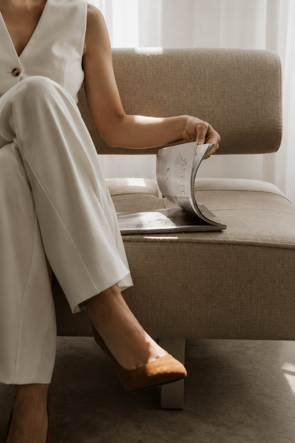 Vrouw in een lichte ruimte leest een magazine op een sofa
